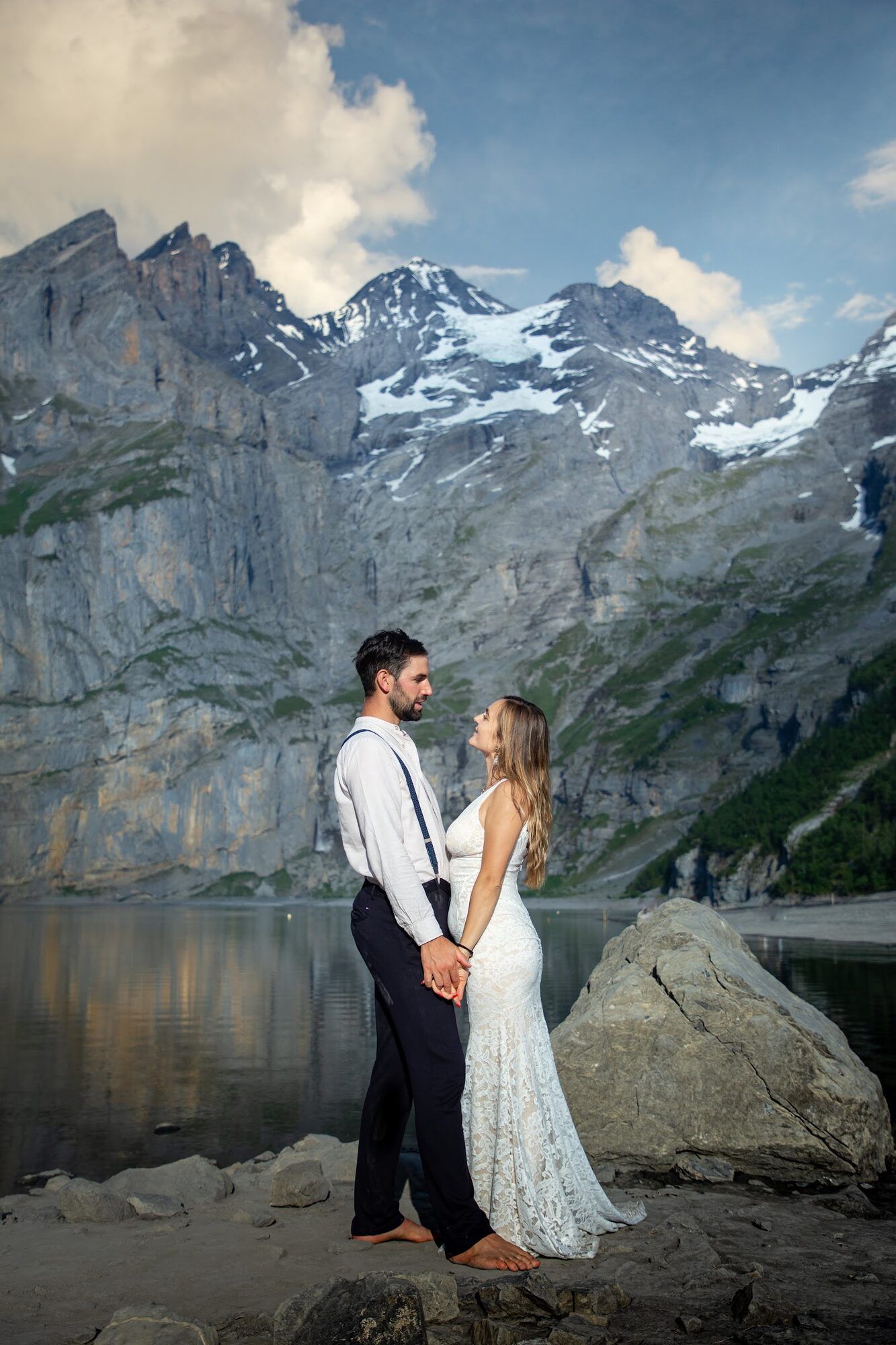 Couple standing by a mountain lake under high cliffs