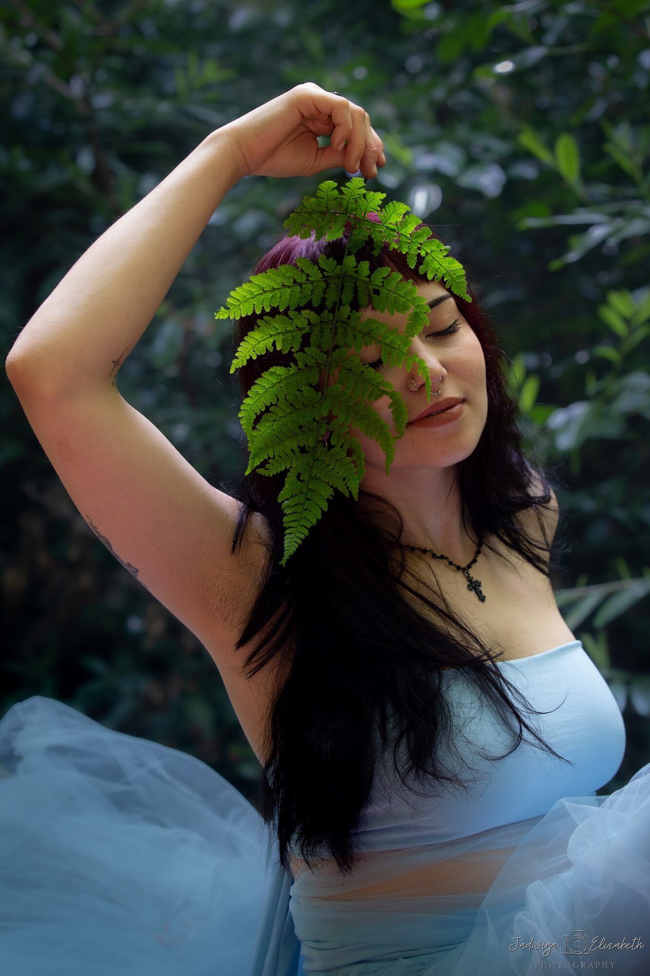 Woman holding a fern above her face