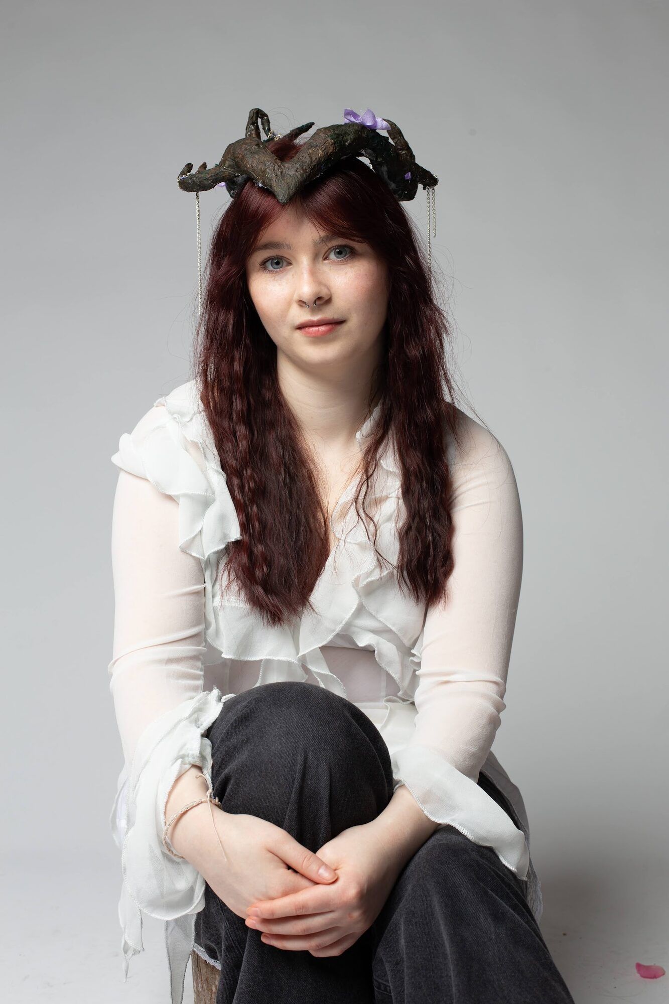 Młoda kobieta w opasce z rogami, na siedząco