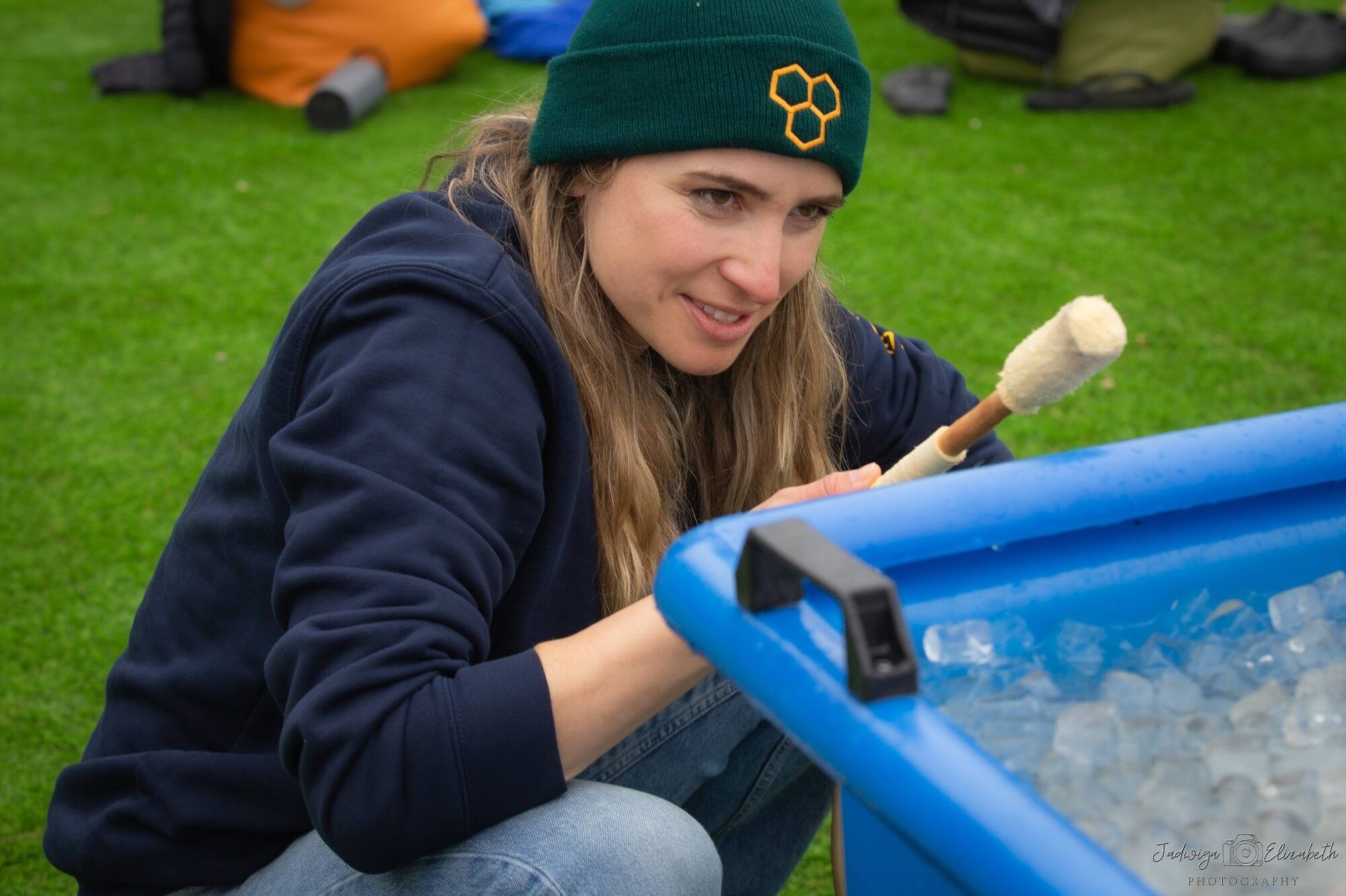 The same woman kneeling by a blue ice bath